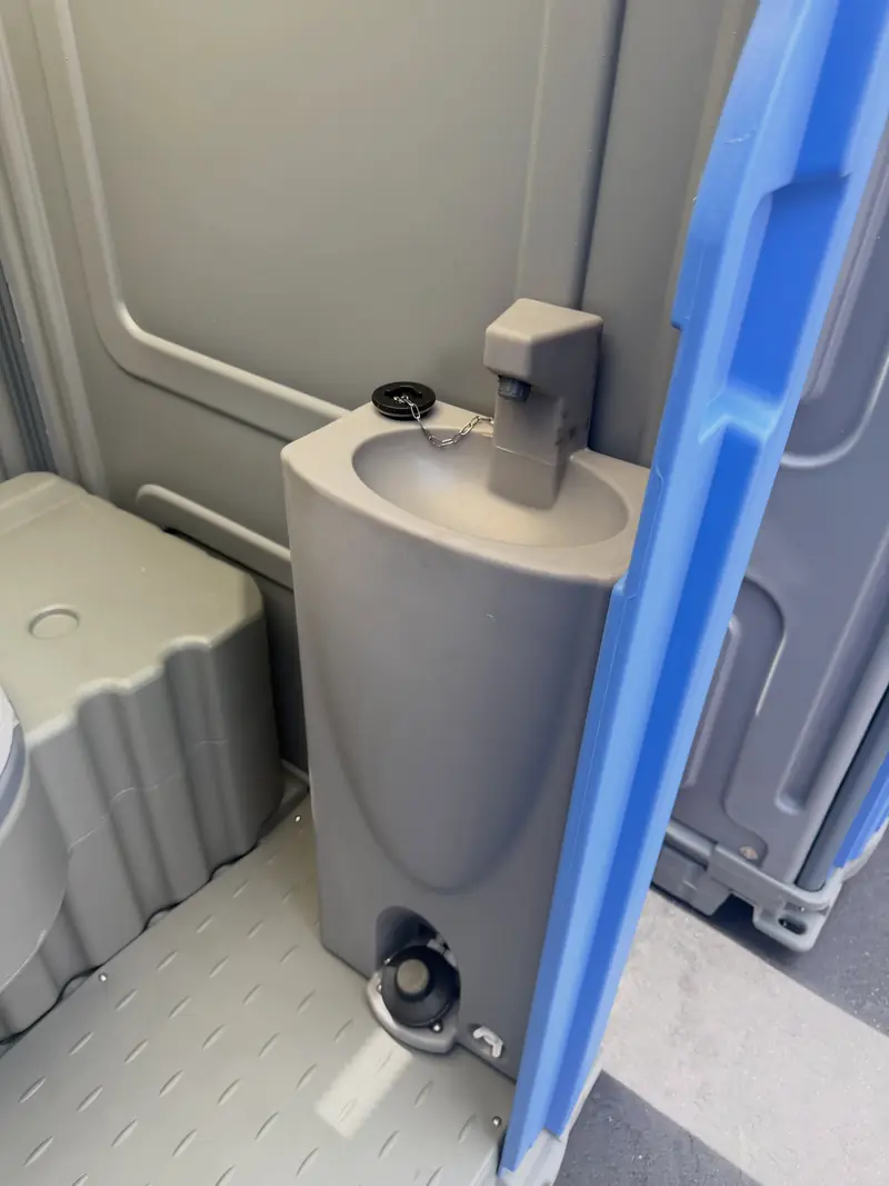 Foot-pump hand-washing sink built into a deluxe portable toilet, no water hookup required
