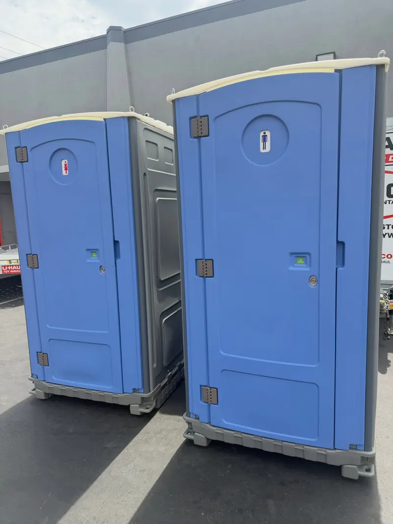 Two standard blue portable toilets with translucent roofs ready for delivery